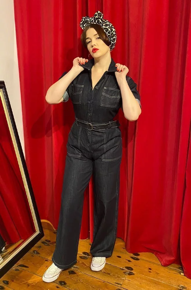 Grease Monkey Jumpsuit. Cut in blue denim with cream stitching, it also features a matching belt and “D” ring buckle. By Freddies of Pinewood