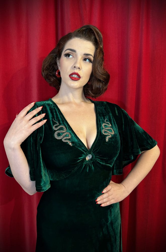 The Snake Maxi Dress is a bewitching 1970s-style maxi dress - crafted in emerald green velvet, with golden snakes & keyhole detail.