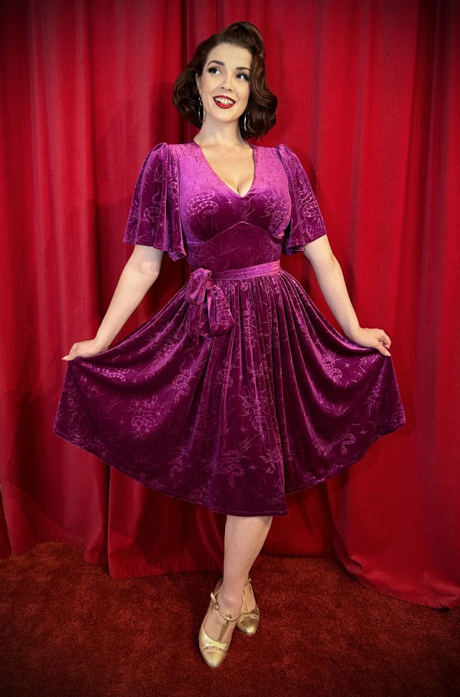 The Snake Velvet Swing Dress is a vintage-inspired dress in luxurious magenta velvet, with embossed snake details, with hidden pockets!